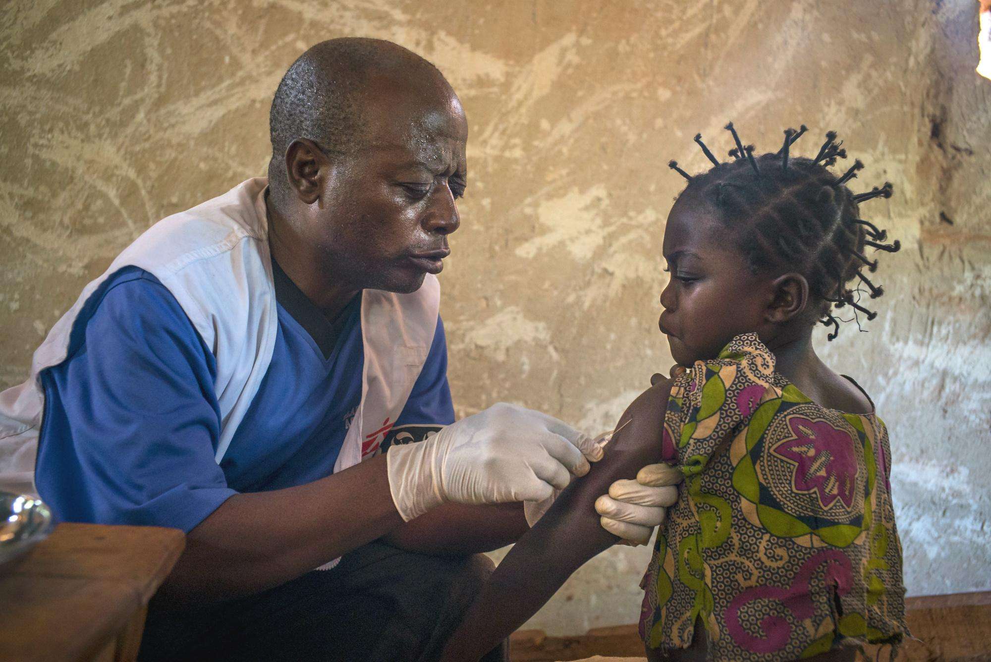 MSF staff member gives a measles vaccination to a young girl
